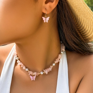 Dettaglio della collana e degli orecchini con farfalla rosa indossati per l'estate