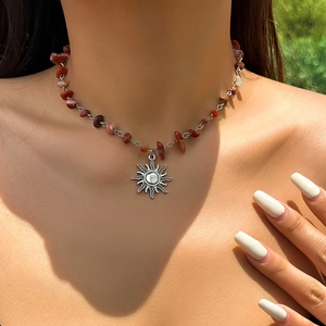 Detail of silver sun pendant necklace with irregular red-brown natural stone beads