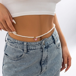 Elegant pearl body chain with a pink butterfly pendant worn over denim pants