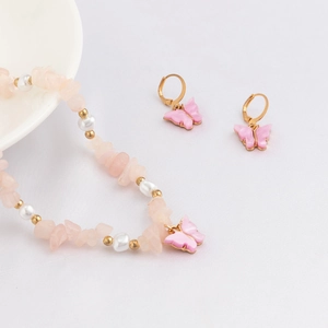 Dettagli di cristalli rosa, perle bianche e set di gioielli con farfalla dorata