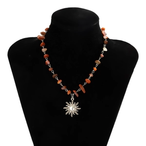Detail of sun pendant necklace with irregular red stone beads on black velvet mannequin