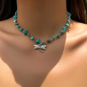 Detail of dragonfly pendant on a bohemian necklace with turquoise stones worn by a model