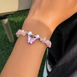 Dettaglio del ciondolo a farfalla e perline rosa sul bracciale da donna