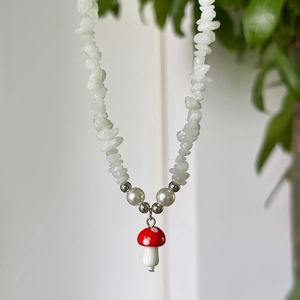 Macro view of a red mushroom pendant on a colorful irregular crushed stone necklace