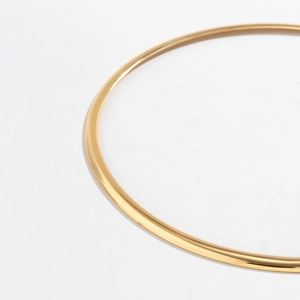 Detail of minimalist golden metal choker necklace with polished surface and smooth round line