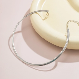 Polished silver metal choker necklace with adjustable chain on elegant ceramic props