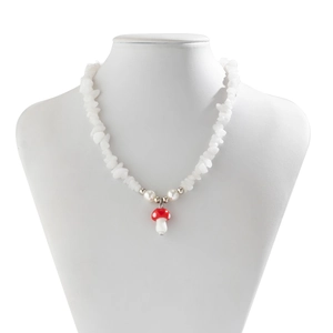 Detail of beaded necklace with white stone chips, red mushroom charm and pearls on neck model