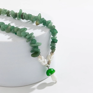 Detail of green stone necklace featuring pearl accents and a mushroom pendant