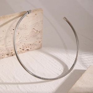 Minimalist silver metal choker collar resting on natural stone prop with polished finish