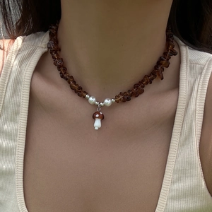 Detail of mushroom pendant on beaded necklace with irregular brown stones and white pearls