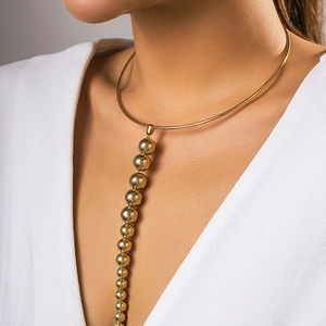 Detail eines polierten goldenen Chokers mit vertikalem Perlenanhänger am Model