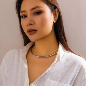 Minimalist silver metal choker necklace with a polished finish worn on a model