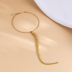 Nahaufnahme eines goldenen Metall-Chokers mit abgestuften Perlen und Karabinerverschluss
