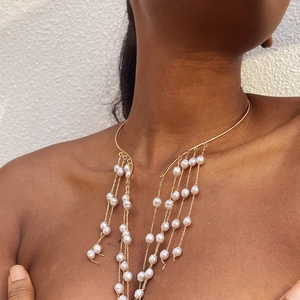 Close-up of golden choker with elegant hanging pearl tassels worn on a model's neck