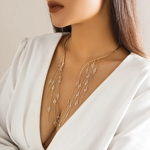Close-up of gold layered tassel choker with crystal accents on a white neckline