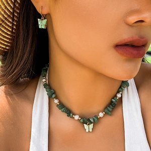Collana a farfalla estiva con pietre verdi e perle indossata da una modella al sole
