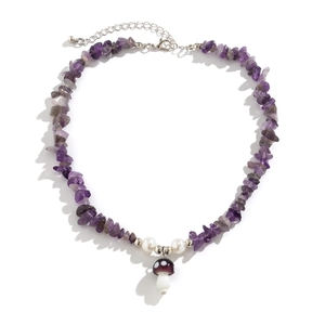 Macro detail of purple gemstone chips and a small glass mushroom pendant on a silver chain