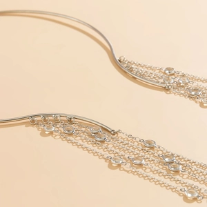 Detail of silver long tassel choker necklace with hanging crystals on a beige background