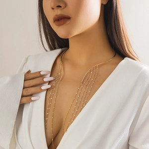 Detailed view of a gold-plated tassel necklace on a model wearing a white suit blazer