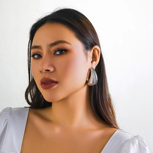 Close-up of a model wearing a large silver teardrop earring with mirror polished finish