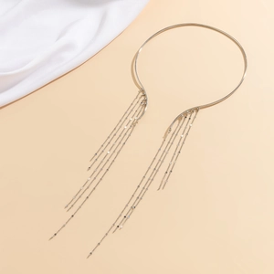 Macro detail of silver tassel choker necklace with hanging metal discs and polished ring