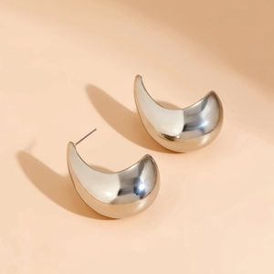 Close-up of chunky silver C-shape stud earrings with a polished mirror finish surface