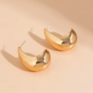 Macro shot of polished gold water drop earrings with fluid metallic curvature detail