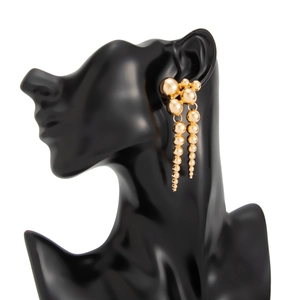 Détail de boucles d'oreilles boules dorées sur mannequin noir pour un look métal élégant