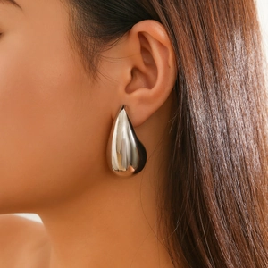Macro shot of silver waterdrop earrings with a polished mirror finish on model