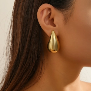 Macro view of polished golden teardrop earrings showing high-gloss metallic finish