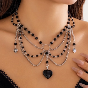 Nahaufnahme eines schwarzen Herzanhängers an einem mehrlagigen Choker bei einem Model