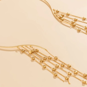 Detail of gold choker necklace with long tassel chains and delicate star pendants