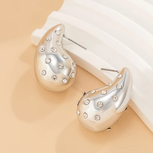Macro detail of silver-tone teardrop earrings with sparkling crystal pavé settings