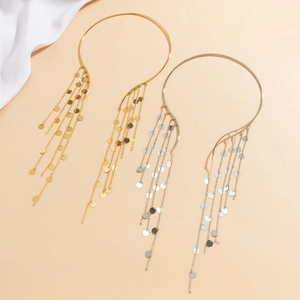 Close-up of gold and silver long tassel earrings with metallic sequins on beige fabric