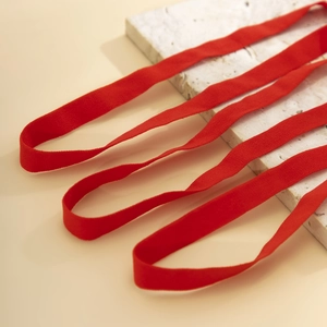 Macro detail of red velvet elastic leg chain band with soft matte texture on stone base