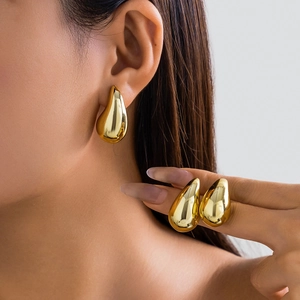 Close-up of elegant polished gold teardrop earrings with liquid metal texture on model