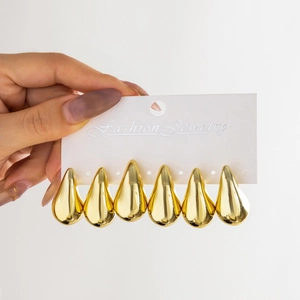 Close-up of six gold teardrop earrings with mirror-polished finish on a display card