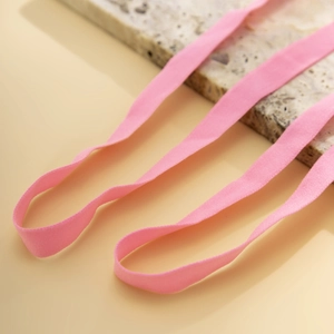 Close-up of pink elastic leg chain straps with high-stretch woven texture on marble