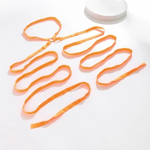Detail van de feloranje elastische beenketting met metalen ringen op een witte achter
