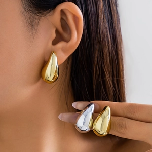 Close-up of gold and silver teardrop earrings with a mirror-polished finish on a model
