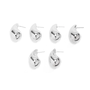 Macro detail of polished silver teardrop earrings with mirror finish surface on white backdrop