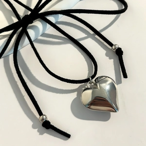 Macro view of large polished heart pendant with black velvet cord and silver metallic beads