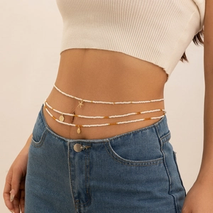 Detail van de drielaagse witte kralen tailleketting met zeester- en schelphandhangers
