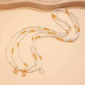 Detail van kralen heupketting met goudkleurige zeester, schelp en levensboom hanger