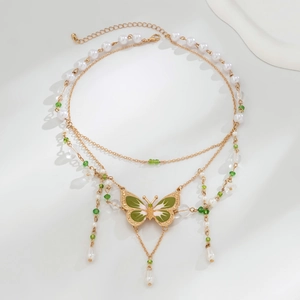 Detail der mehrlagigen Goldkette mit grünem Schmetterlingsanhänger und Perlen