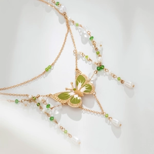 Detailansicht eines goldenen Schmetterlings-Chokers mit grüner Emaille und Perlenketten