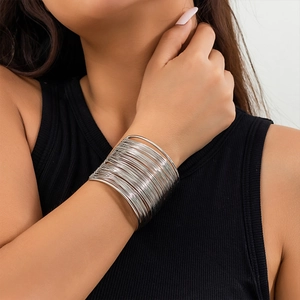 Close-up of a wide silver-toned multi-layer metal cuff bracelet worn on an arm