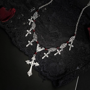 Detailed shot of gothic silver cross necklace with red beads on black lace backdrop