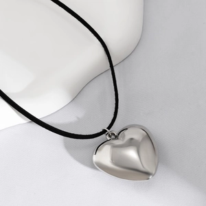 Close-up of polished heart pendant with minimalist black cord on a ceramic plate
