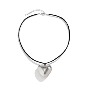 Macro detail of polished silver heart pendant with black cord and lobster clasp closure